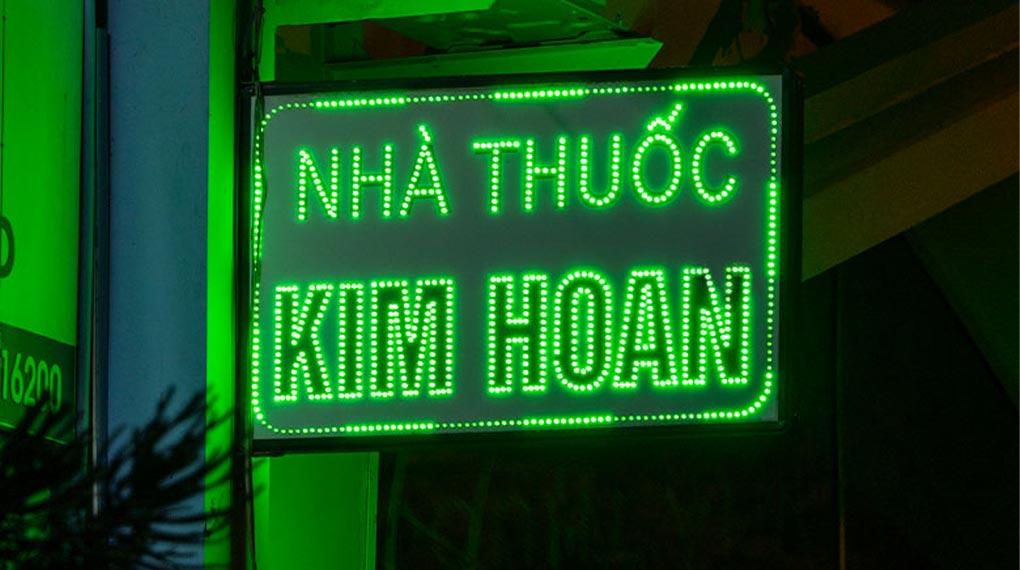 Bảng hiệu thuốc tây với ánh sáng đèn neon nổi bật giữa các cửa hàng bang hieu tiem thuoc tay 1020x570 3